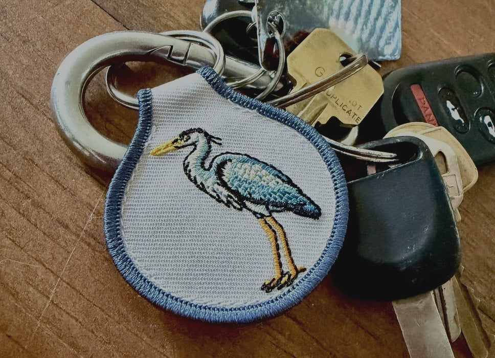 Embroidered heron patch keychain clipped to a set of car keys